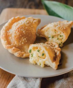 a whole cheese samosa and a samosa cut in half, on a plate