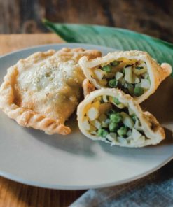 bali buda vegetable samosas, one whole, and one cut in half, on a plate