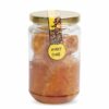 A jar containing raw red honey and honeycomb
