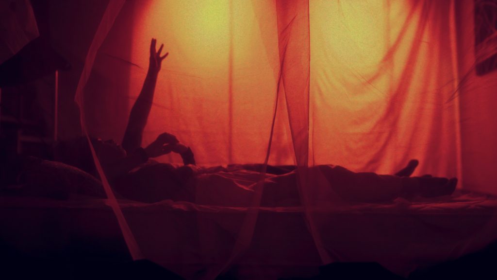 People lying down under a mosquito net, at night