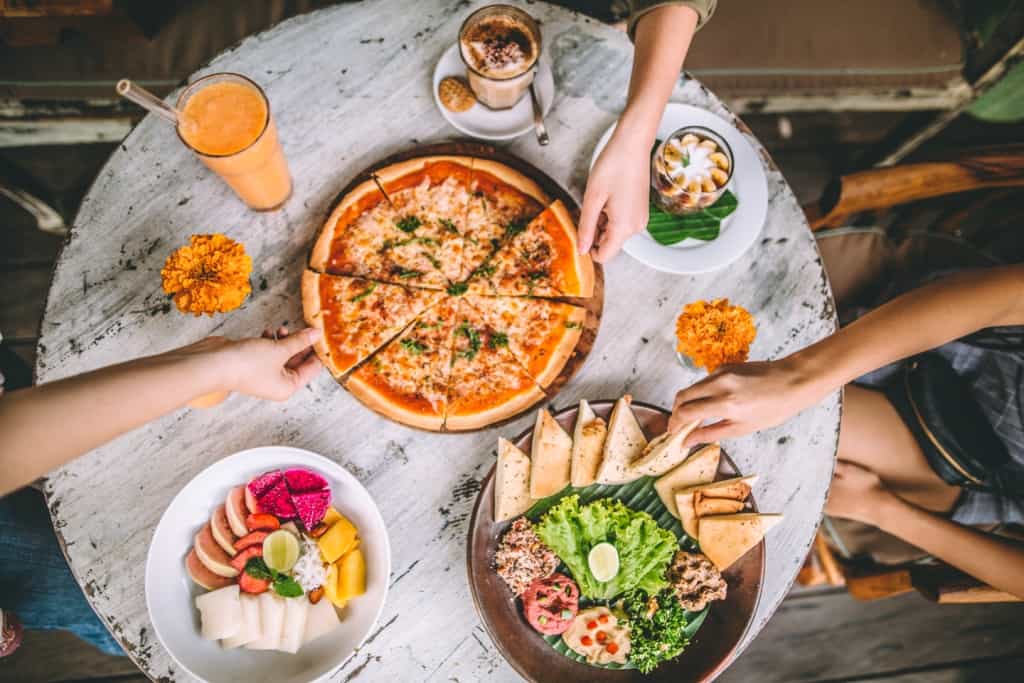 Bali Buda dishes set on a table, pizza, organic fruit salad and coffee