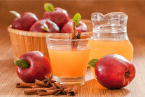 apple cider vinegar with mother, displayed in a glass with apples around, on a table