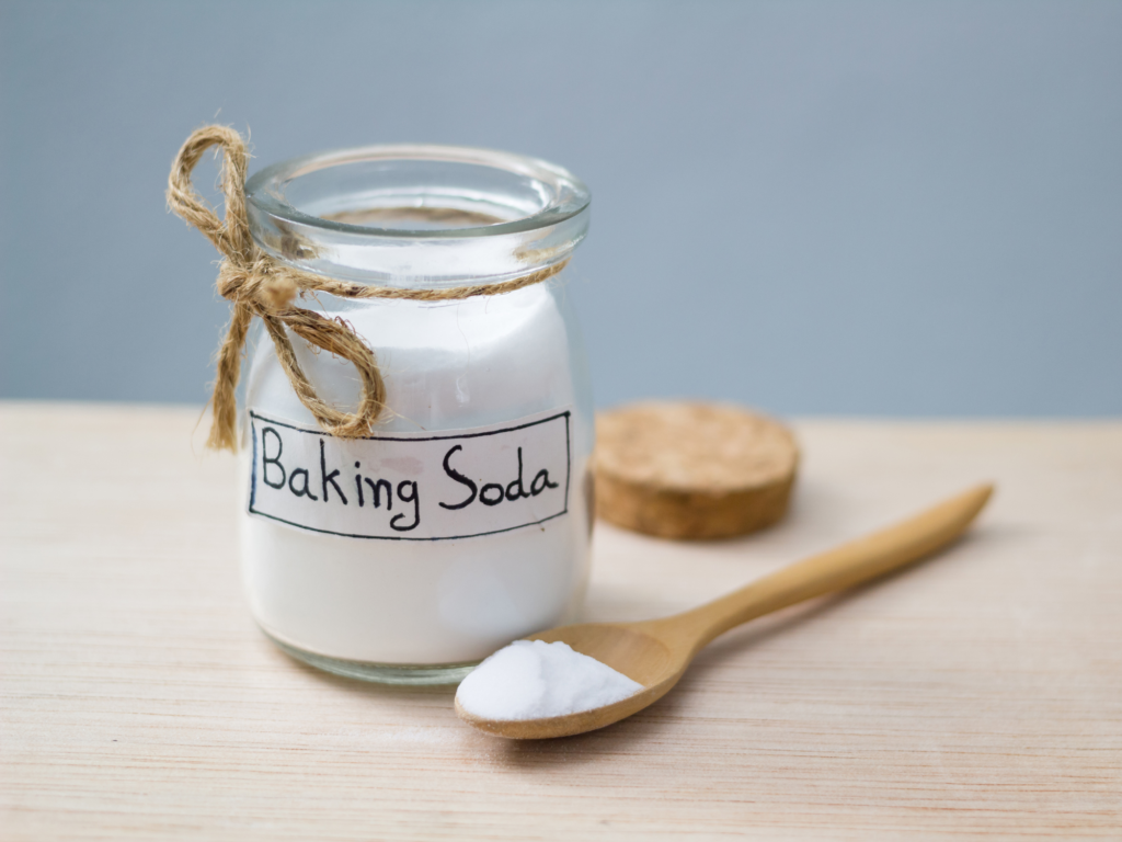 a jar of baking soda and a wooden spoon, on a table