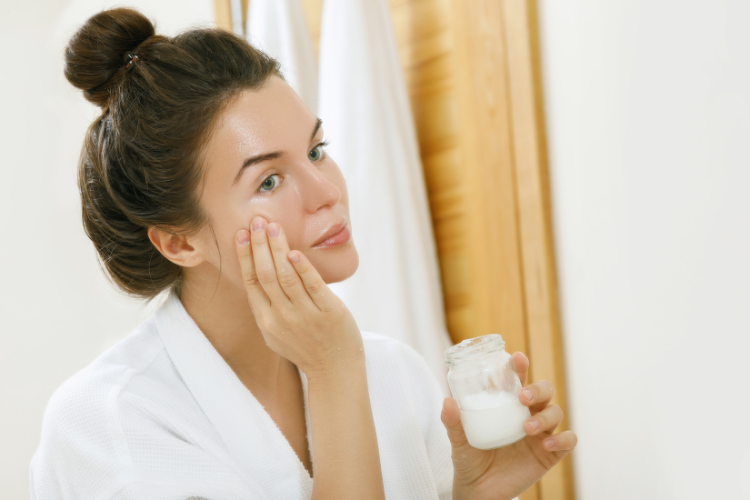 A woman applying Bali Buda cold-pressed virgin coconut oil on her face