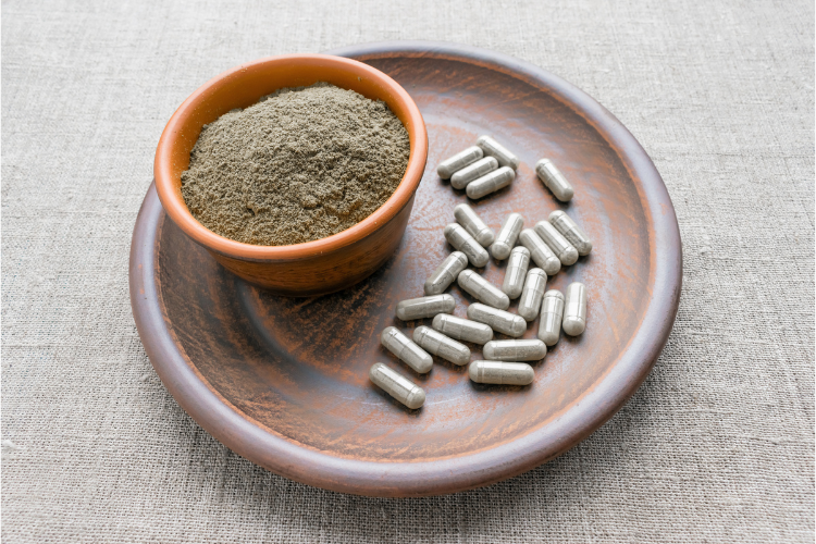 A bowl of neem powder and neem capsules on a plate