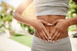 A woman forming a heart with her hands, on her belly